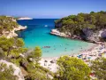Rajska zatoka z turkusową wodą i piaszczystą plażą, pełna ludzi. To jedna z najpiękniejszych plaż w Hiszpanii.