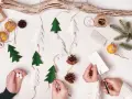 Kinder basteln Weihnachtsgeschenke: Papierbäume, Zapfen und Orangen werden zu einer festlichen Girlande.
