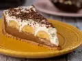 Kawałek banoffee pie z bananami, kremem i czekoladą na żółtym talerzu. Nie tarta cytrynowa, ale pyszny deser!