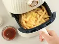 Air fryer co to? To urządzenie, które przygotuje chrupiące frytki bez nadmiaru tłuszczu. Obok sosy i majonez.