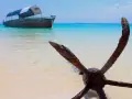 Kotwica na plaży, łódź na turkusowym morzu. Idealne miejsce na Zanzibar wycieczki fakultatywne.
