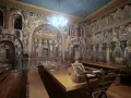 Inside Mount Athos, a refectory is adorned with ancient frescoes depicting religious scenes and figures.