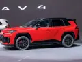 Czerwony, tani SUV z czarnym dachem i felgami, prezentowany na wystawie obok białego modelu.