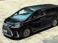 Elegancki, czarny Lexus LM 350h lśni na tle jasnej kostki brukowej.