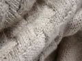 Tessuto a maglia grossa color crema, con un motivo a trecce che ricorda la morbidezza della flanella.