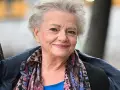 Uśmiechnięta Anna Seniuk, ikona polskich filmów, seriali i programów, w kolorowym szalu i granatowej kurtce.