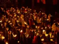 A solemn vigil unfolds as a congregation holds candles, their faces illuminated by the soft glow.