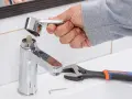 Mano desmontando grifo monomando. Llave inglesa y llave Allen cerca.