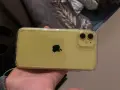 Żółty iPhone 11 w przezroczystym etui, trzymany w dłoni.