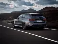 Mocne BMW M5 Touring pędzi po krętej drodze pośród surowego krajobrazu.