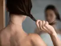 Kobieta w lustrze skręca włosy, myśląc o domowej odżywce z wody ryżowej dla ich wzmocnienia.