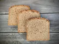 Drei Scheiben **Vollkornbrot** aus der **Kastenform** liegen auf rustikalem Holz.