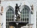 Fontanna Neptuna w Gdańsku, z bogatą rzeźbą boga mórz na tle zabytkowej kamienicy.