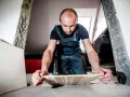 Budowlaniec ostrożnie podważa płytkę, pokazując, jak skuć płytki bez uszkodzenia.