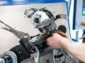 Mechanik pracuje nad turbosprężarką, mocując ją imadłem. Widoczny jest zawór N75, kluczowy element sterujący pracą turbiny.