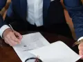 Mężczyzna w garniturze podpisuje dokument, składając oświadczenie woli.