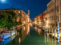 Una gondola venezia di notte, con luci soffuse che si riflettono sull'acqua e un cielo stellato.