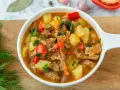 Aksamitna, aromatyczna najlepsza zupa gulaszowa z kawałkami mięsa, ziemniaków i papryki, posypana świeżą natką pietruszki.