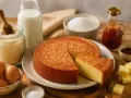 Un délicieux gâteau de semoule, doré et moelleux, entouré de ses ingrédients : œufs, lait, sucre, semoule, beurre et sirop.