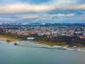 Widok na Płock z lotu ptaka, z Wisłą w tle. Widać panoramę miasta, fabryki z dymiącymi kominami i nowoczesną infrastrukturę nad rzeką, która może być częścią atrakcji dla dzieci w Płocku.