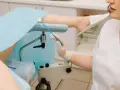 Lekarz przygotowuje się do gbs badanie, trzymając wymazówkę. Pacjentka leży na fotelu ginekologicznym.