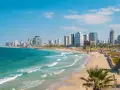 Słoneczna tel aviv plaża z turkusową wodą i nowoczesnymi wieżowcami w tle.