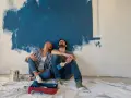 Coppia seduta sul pavimento, guarda in alto verso un muro dipinto di blu. Stacco tra parete e soffitto si o no?