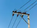 Słupy energetyczne z izolatorami ceramicznymi i przewodami pod napięciem. Brak zgody na służebność przesyłu może oznaczać problemy z infrastrukturą.