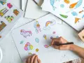 Une main dessine des licornes, des maisons et des bonbons, une scène parfaite pour une formation illustrateur jeunesse.