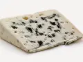 Un trozo de queso azul con vetas oscuras, un queso que huele mal pero es delicioso.