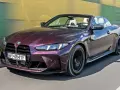 Fioletowe BMW M4 Competition kabriolet pędzi po drodze, odsłaniając białe wnętrze i sportowe detale.