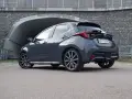 Szary Toyota Yaris GR Sport z czarnym spojlerem i dyfuzorem, zaparkowany przed tunelem.