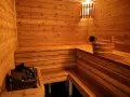 Drewniana sauna z kamieniami i wiadrem. Inspiracja, jak zbudować saunę, by cieszyć się relaksem.