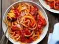 Un piatto fumante di spaghetti conditi con un ricco sugo all'amatriciana ricetta della nonna, cosparso di formaggio grattugiato.