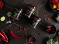 Słoiki z kimchi, papryczki chili, ogórek i przyprawy na czarnym tle.