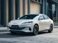 Biały BYD Seal 6 DM-i sunie ulicą, otoczony miejską architekturą.