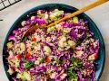 En färgstark couscous sallad med rödkål, äpple och färska örter. En gyllene sked vilar i den fräscha salladen.