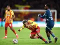 Piłkarz RC Lens w żółto-czerwonym stroju walczy o piłkę z zawodnikiem Stade Rennais.