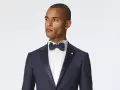 Uomo con abito nero e cravatta blu, pronto per un evento elegante.