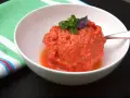 Ein erfrischendes Tomaten-Eis, garniert mit Basilikum, in einer weißen Schüssel.