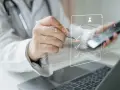 Lekarz w białym kitlu analizuje dokumenty na ekranie, w tym potencjalne zwolnienie lekarskie od psychiatry płatne 100%.