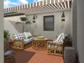 Ideas para decorar patios pequeños con poco dinero: muebles de ratán, cojines a cuadros y plantas crean un oasis acogedor.