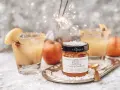 Dwa drinki z whisky i sokiem jabłkowym, ozdobione jabłkiem i cynamonem, na tle fajerwerków. Słoiczek z cytrusami i cynamonem.