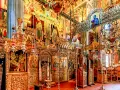 Interior of a richly decorated Orthodox church, showcasing ornate iconostasis, frescoes, and chandeliers, typical of many ancient christian monasteries.