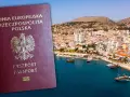 Polski paszport na tle malowniczego wybrzeża. Czy do Austrii trzeba mieć paszport? Tak, nawet do krajów UE, jeśli nie masz dowodu osobistego.
