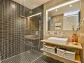 A modern bathroom with a walk-in tiled shower. Learn how to clean a walk-in tiled shower with this stylish setup.