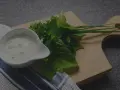 Sauce tartare maison crémeuse dans un ramequin blanc, accompagnée d'herbes fraîches sur une planche en bois.