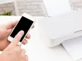 Instrukcja, jak połączyć drukarkę z telefonem, pokazana na przykładzie smartfona i białej drukarki.