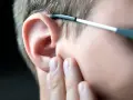 Dłoń dotyka ucha, sugerując uczucie zatkanego ucha. Okulary opierają się o skroń.