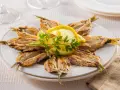 Piatto di alici alla scapece disposte a raggiera, guarnite con fette di limone e prezzemolo.